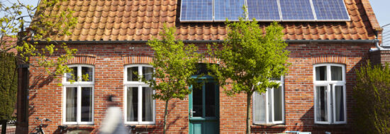 Small house with solar panel. A person on a bike drives by in the foreground.